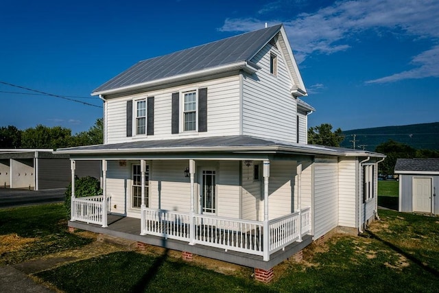 country-style home featuring a front yard, covered porch, and a storage unit