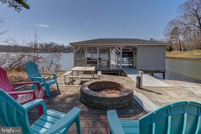 exterior space featuring a water view, a patio, and an outdoor fire pit