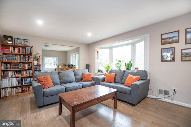 living room with light wood-style flooring, visible vents, and baseboards