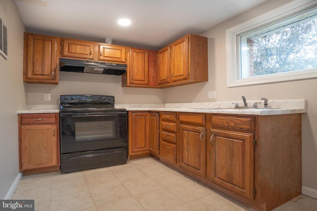 kitchen with brown cabinets, black range with electric stovetop, light countertops, under cabinet range hood, and a sink