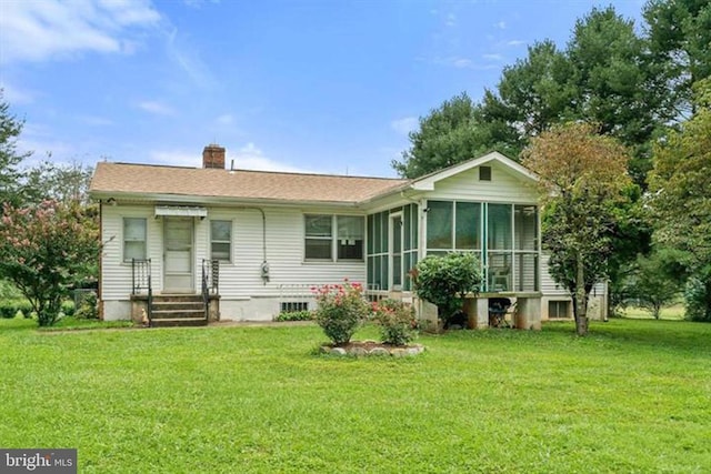 back of house with a sunroom, a yard, and a chimney