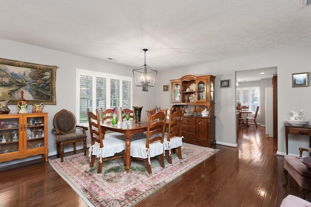 dining space with dark wood-style flooring, baseboards, a notable chandelier, and a textured ceiling