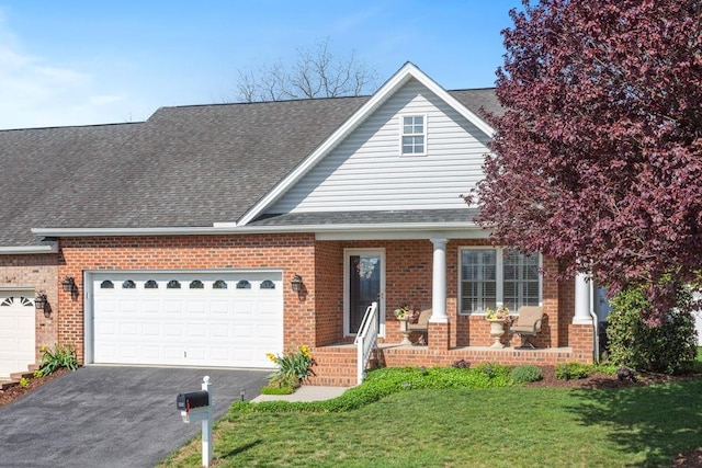 traditional home featuring aphalt driveway, a front yard, roof with shingles, brick siding, and an attached garage