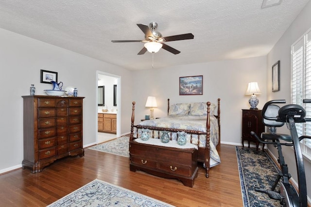 bedroom featuring baseboards, a textured ceiling, ensuite bathroom, and wood finished floors