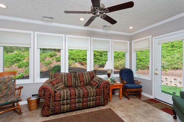 sunroom featuring visible vents, ornamental molding, a textured ceiling, and a healthy amount of sunlight