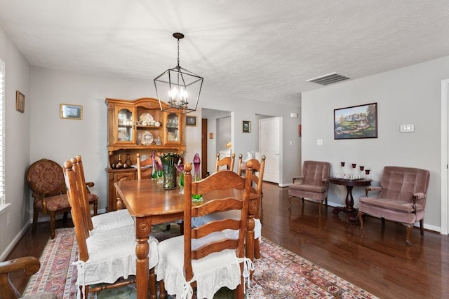 dining area featuring an inviting chandelier, baseboards, wood finished floors, and visible vents