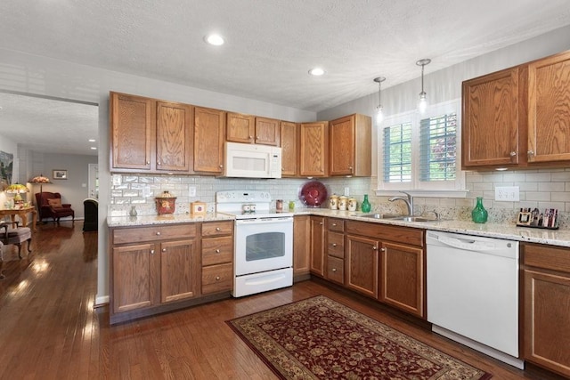 kitchen with a sink, white appliances, brown cabinetry, decorative backsplash, and dark wood-type flooring
