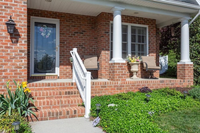 entrance to property featuring a porch and brick siding