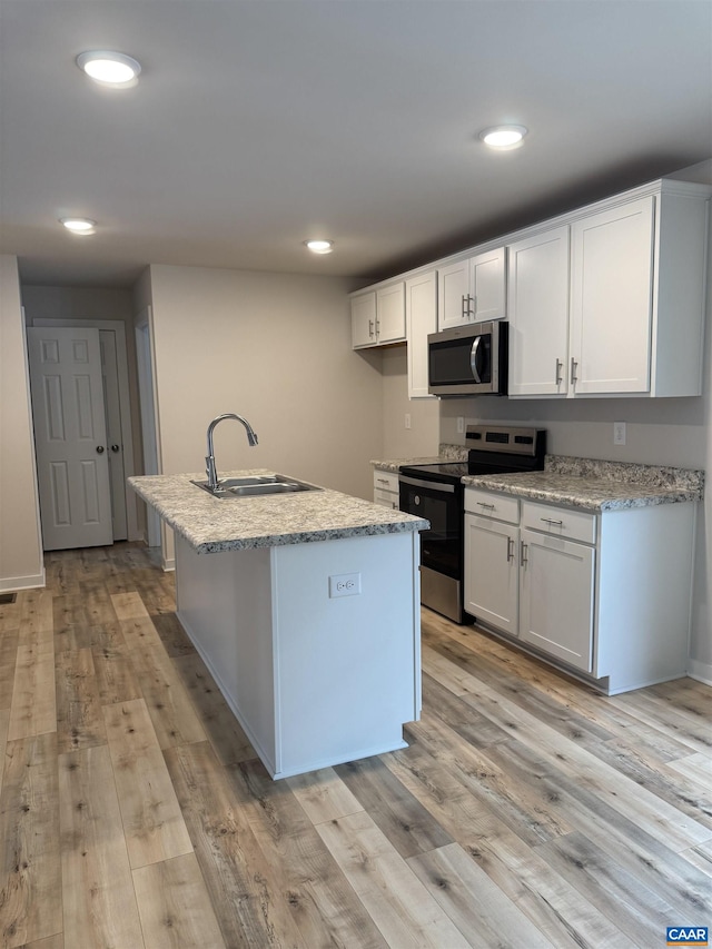 kitchen with sink, white cabinets, stainless steel appliances, a center island with sink, and light hardwood / wood-style flooring