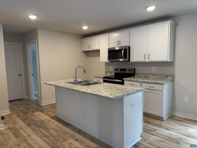 kitchen with electric range oven, white cabinetry, sink, a center island with sink, and light wood-type flooring