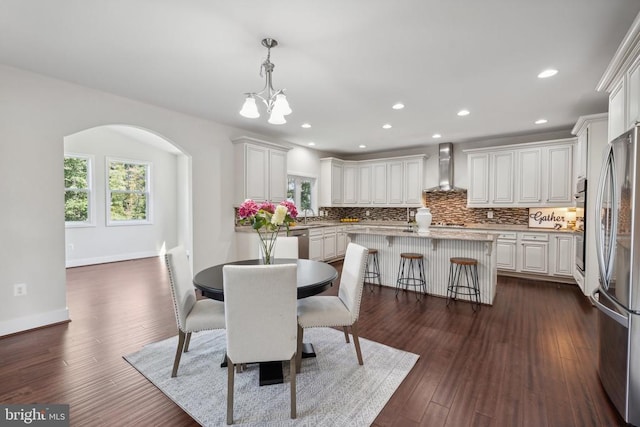 dining area featuring dark wood-style floors, baseboards, arched walkways, and recessed lighting