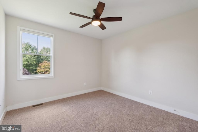 carpeted empty room with a ceiling fan, visible vents, and baseboards