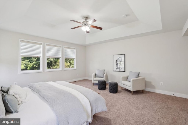 carpeted bedroom featuring baseboards, a tray ceiling, and ceiling fan