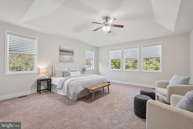 carpeted bedroom featuring a raised ceiling, visible vents, ceiling fan, and baseboards