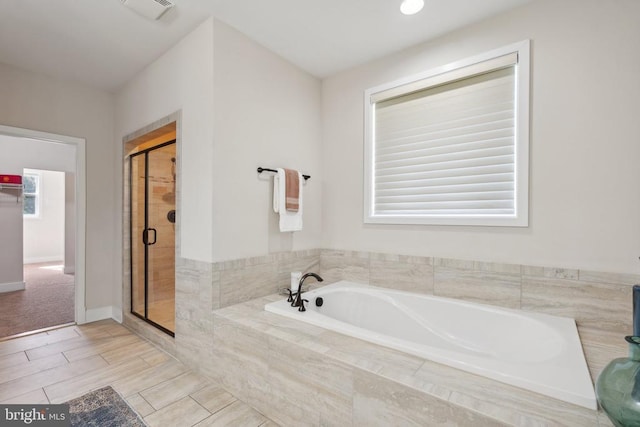 bathroom with a stall shower, a garden tub, visible vents, and baseboards