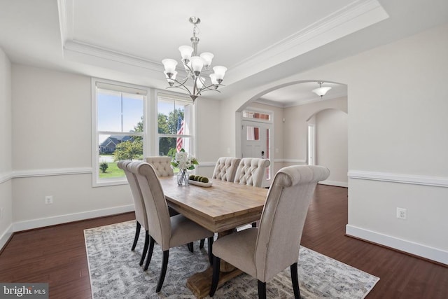 dining space featuring arched walkways, wood finished floors, and a raised ceiling