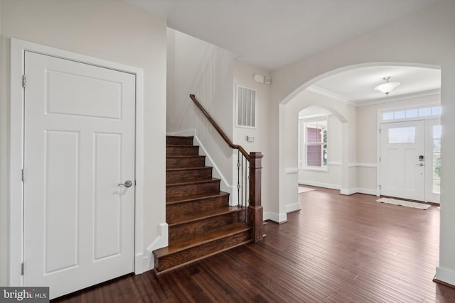 entrance foyer featuring arched walkways, dark wood-style flooring, visible vents, baseboards, and stairs