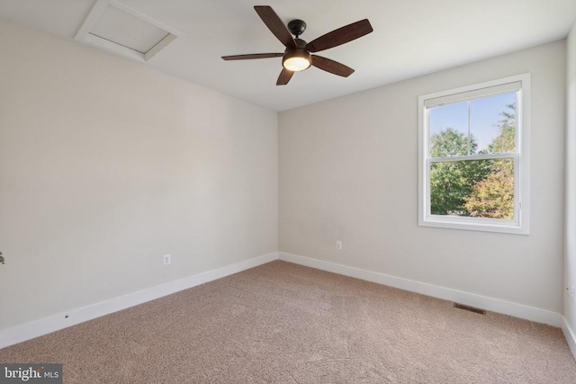 empty room featuring light colored carpet, visible vents, attic access, ceiling fan, and baseboards