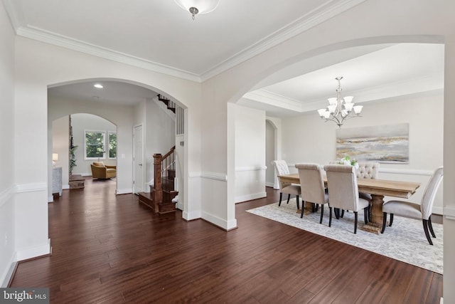 dining area with crown molding, wood finished floors, a chandelier, baseboards, and stairs