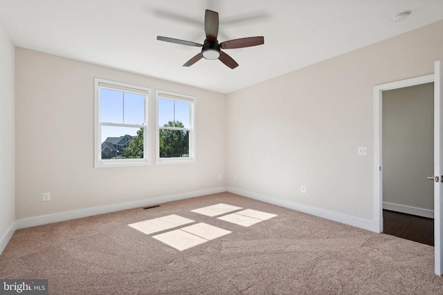 carpeted spare room with ceiling fan, visible vents, and baseboards