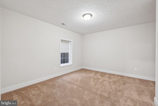 carpeted spare room featuring baseboards, visible vents, and a textured ceiling