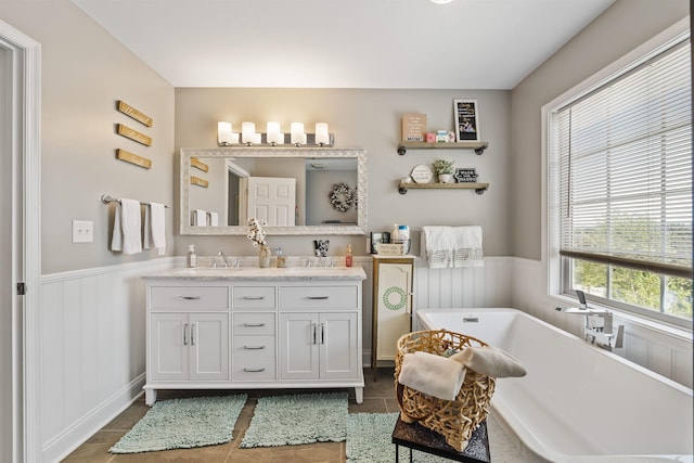 bathroom featuring double vanity, a wainscoted wall, tile patterned flooring, and a freestanding bath