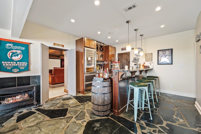 kitchen featuring a breakfast bar area, stone flooring, visible vents, and recessed lighting
