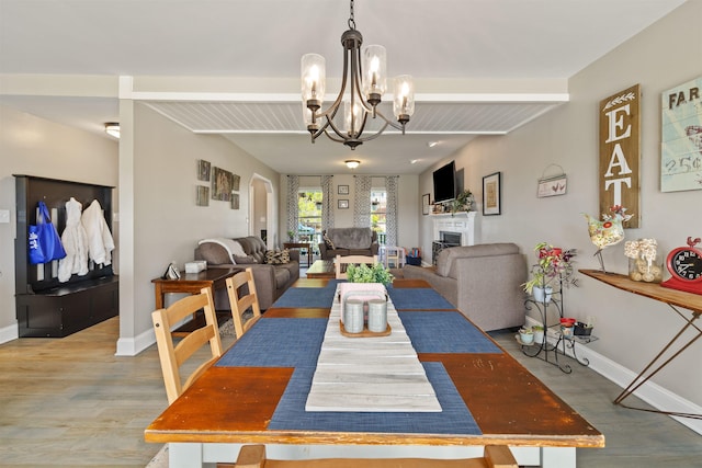 dining area featuring beamed ceiling, wood finished floors, and a fireplace