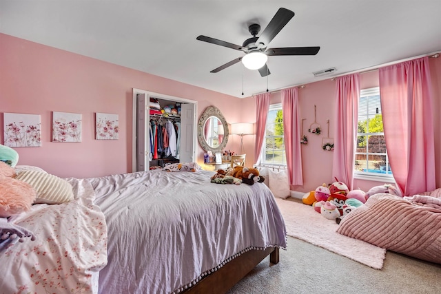 carpeted bedroom with a walk in closet, ceiling fan, and visible vents