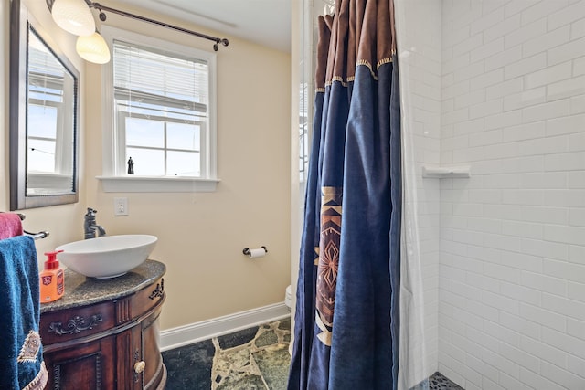 bathroom with baseboards, a tile shower, toilet, and vanity