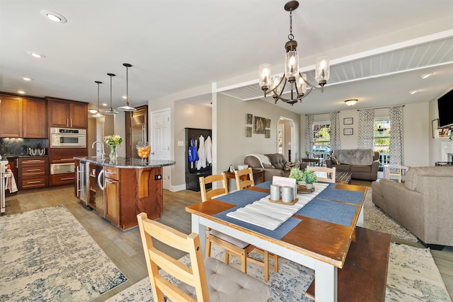 dining space featuring arched walkways, a notable chandelier, recessed lighting, and light wood-type flooring