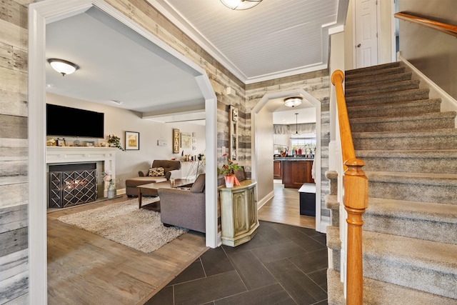 interior space featuring arched walkways, dark tile patterned flooring, baseboards, ornamental molding, and stairs