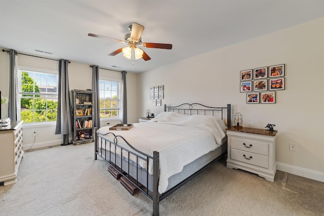 bedroom with baseboards, ceiling fan, visible vents, and light colored carpet