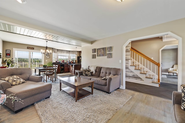 living room featuring arched walkways, wood finished floors, a chandelier, and stairway