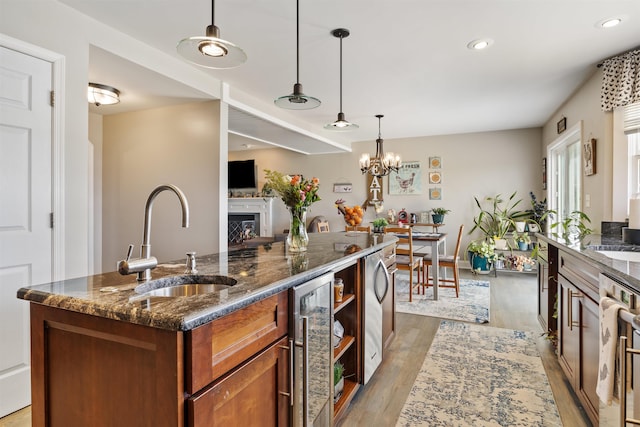 kitchen featuring a sink, light wood finished floors, beverage cooler, brown cabinetry, and recessed lighting
