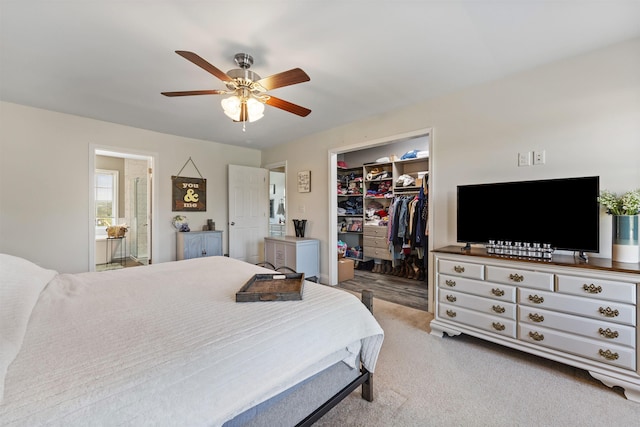 bedroom featuring a walk in closet, a ceiling fan, light colored carpet, a closet, and connected bathroom