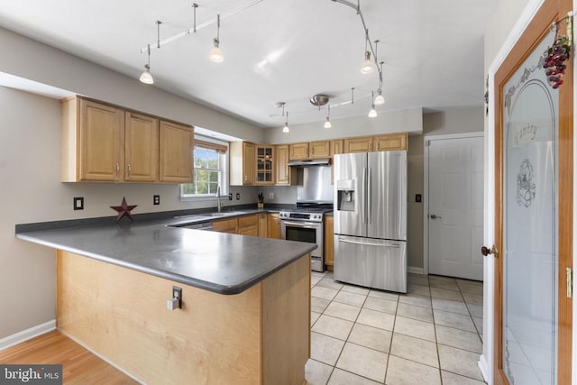 kitchen with stainless steel appliances, dark countertops, glass insert cabinets, a sink, and a peninsula