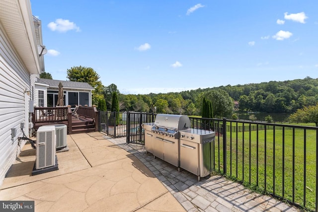 view of patio featuring an outbuilding, a grill, fence, a wooden deck, and a wooded view