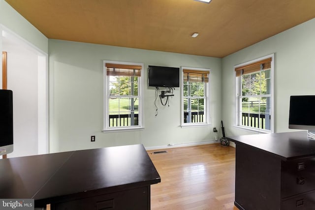 office with a wealth of natural light, light wood-type flooring, visible vents, and baseboards