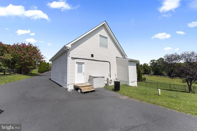 view of side of home with a garage, driveway, a lawn, and fence