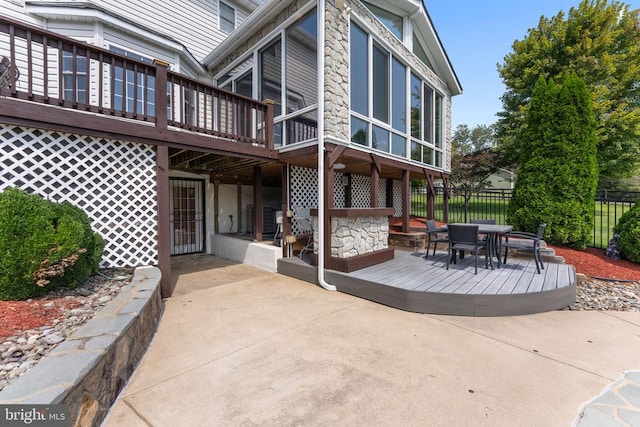 back of property featuring outdoor dining area, fence, a wooden deck, and a patio