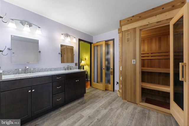 bathroom featuring wood finished floors, double vanity, a sauna, and a sink