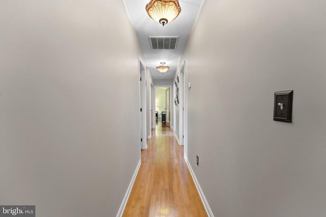 hall with visible vents, light wood finished floors, and baseboards