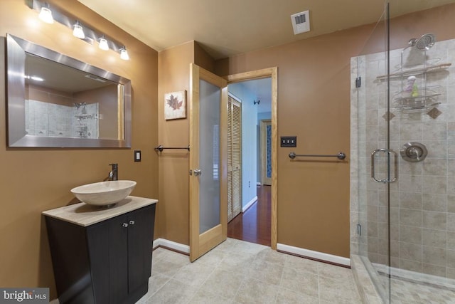 full bathroom featuring a stall shower, vanity, visible vents, and baseboards