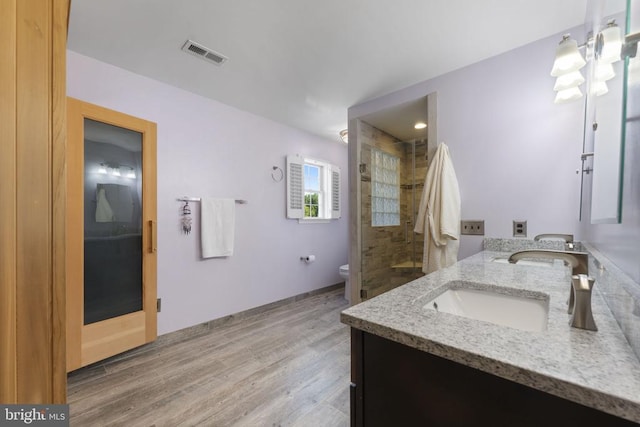 full bath with double vanity, visible vents, toilet, wood finished floors, and a sink