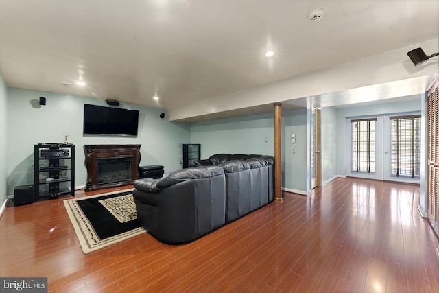 living room with baseboards, a glass covered fireplace, wood finished floors, french doors, and recessed lighting