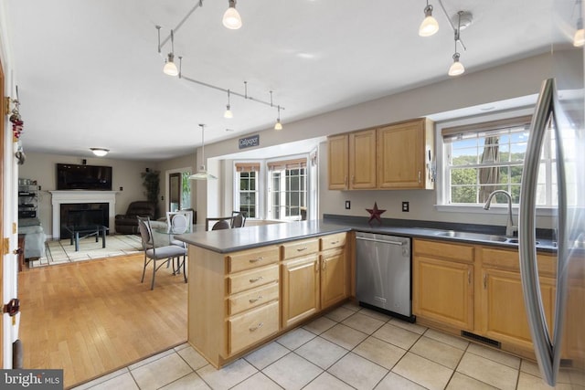 kitchen featuring a fireplace, stainless steel appliances, dark countertops, open floor plan, and a sink