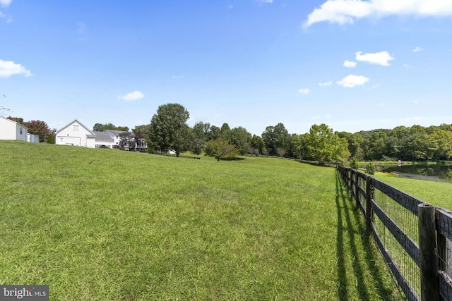 view of yard with fence and a rural view