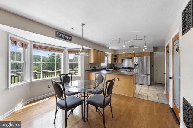 dining room featuring light wood finished floors, track lighting, visible vents, and baseboards