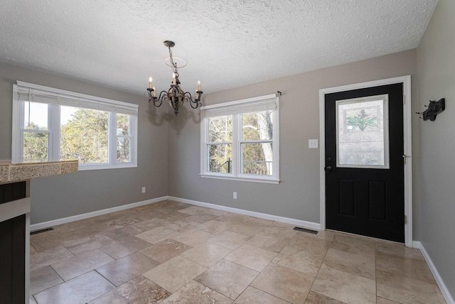 entrance foyer featuring visible vents, a notable chandelier, and baseboards